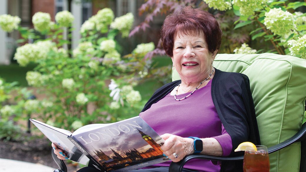 A woman reads a book seated outside.
