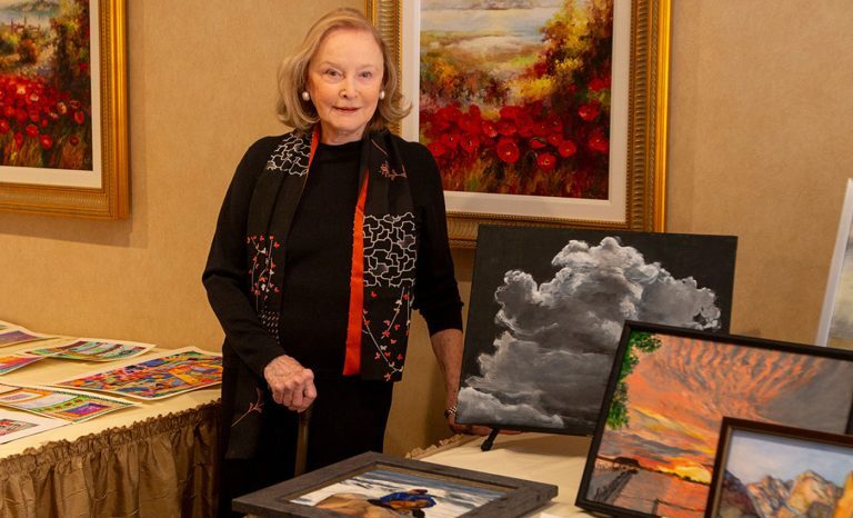 The Gatesworth resident standing next to a display of her paintings.