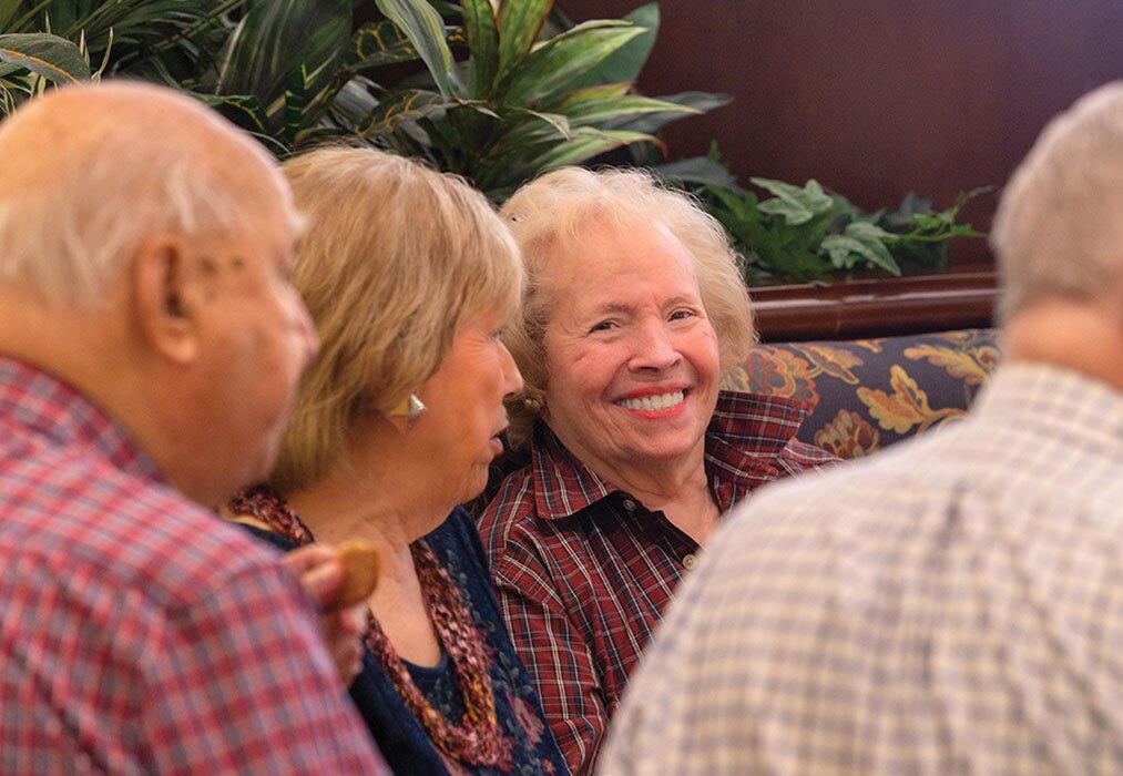 Residents sitting in a booth enjoying each other's company and smiling.