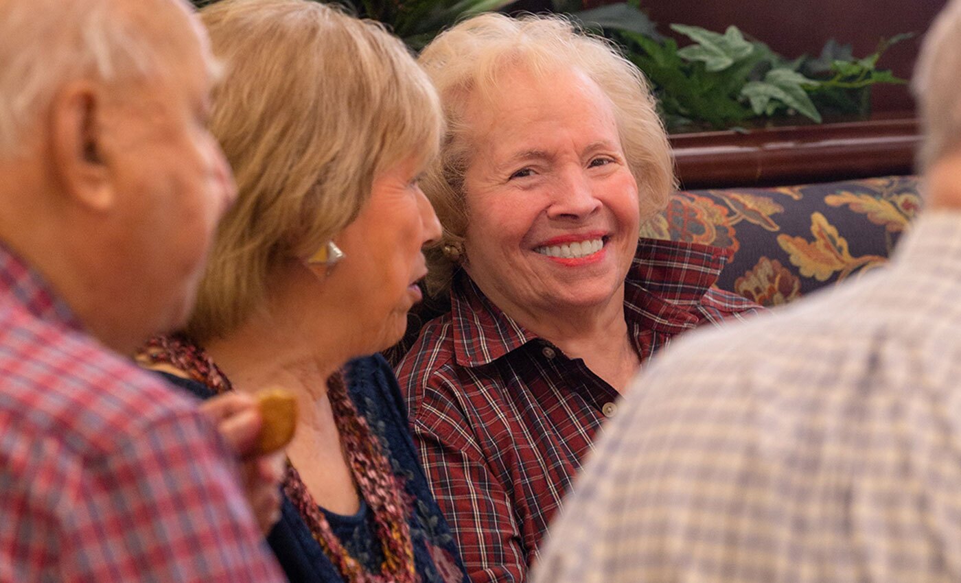 A resident sitting in a booth with others smiling.
