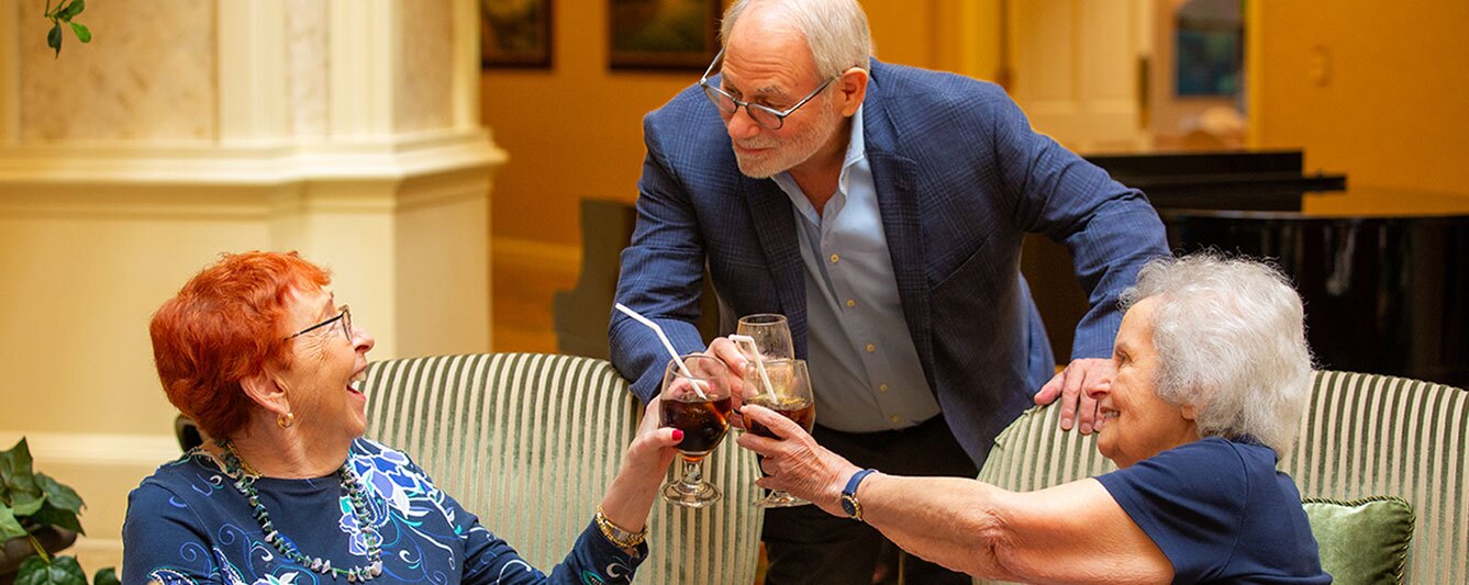Three people clinking their glasses together in a toast.