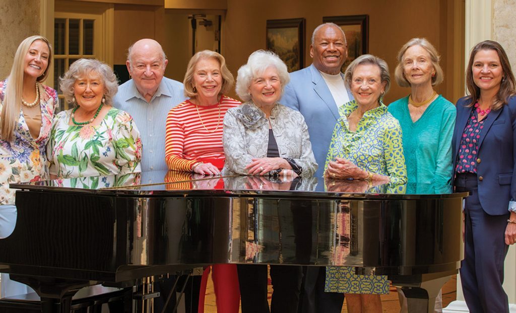 Resident ambassadors standing around a piano.
