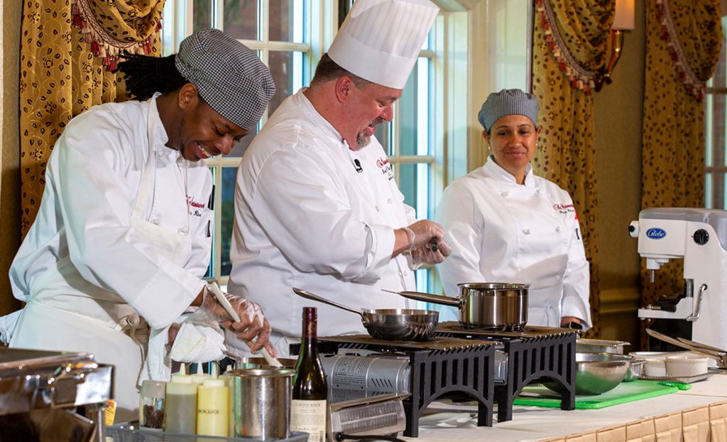 Three chefs cooking food in the dining room.