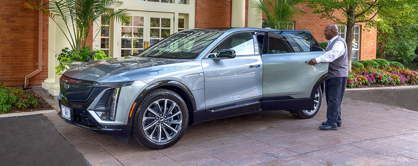 A staff member opens the door of a luxury car.