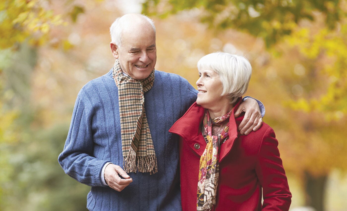 A couple walking outdoors in the fall weather with scarves.