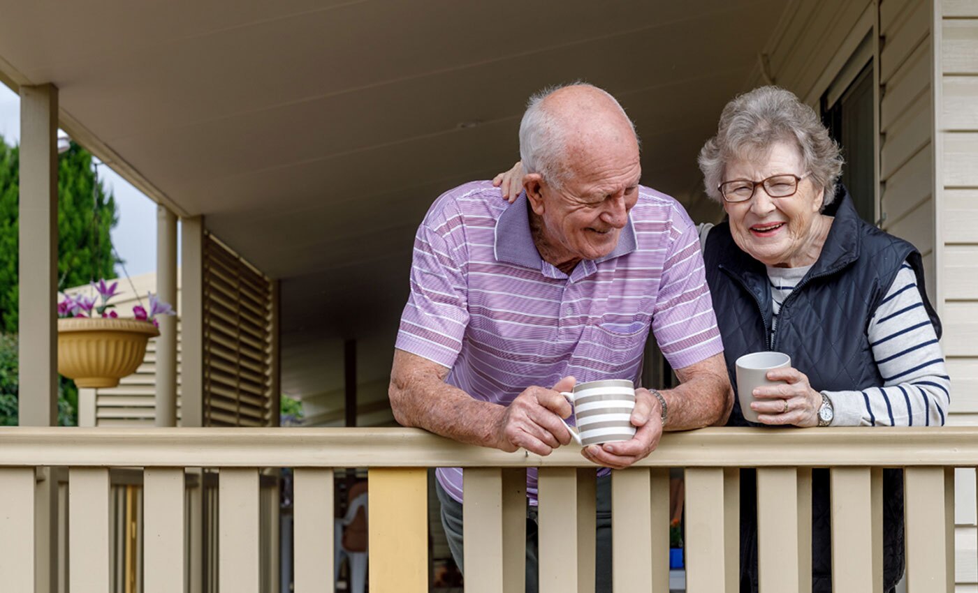 A husband and wife enjoying warm drinks on the porch.