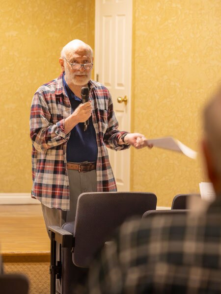 A man holding papers gives a lecture.