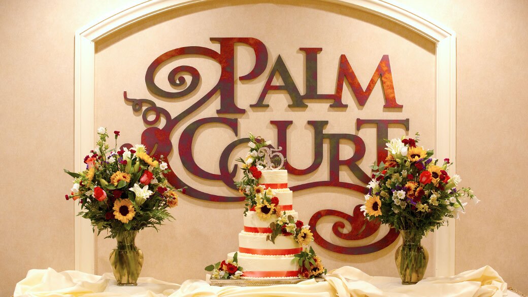 Palm Court sign with flowers and cake.