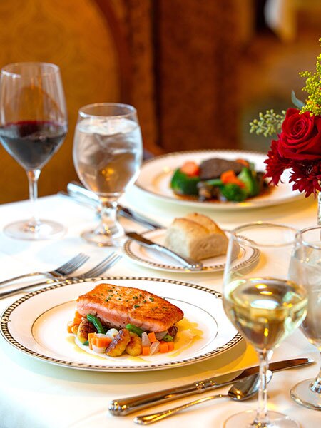 Meals on a table with flowers and wine.