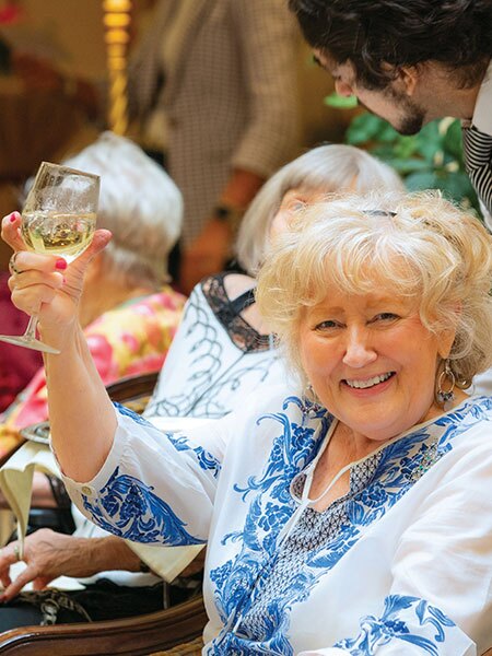 A resident smiling and holding up a glass of wine.
