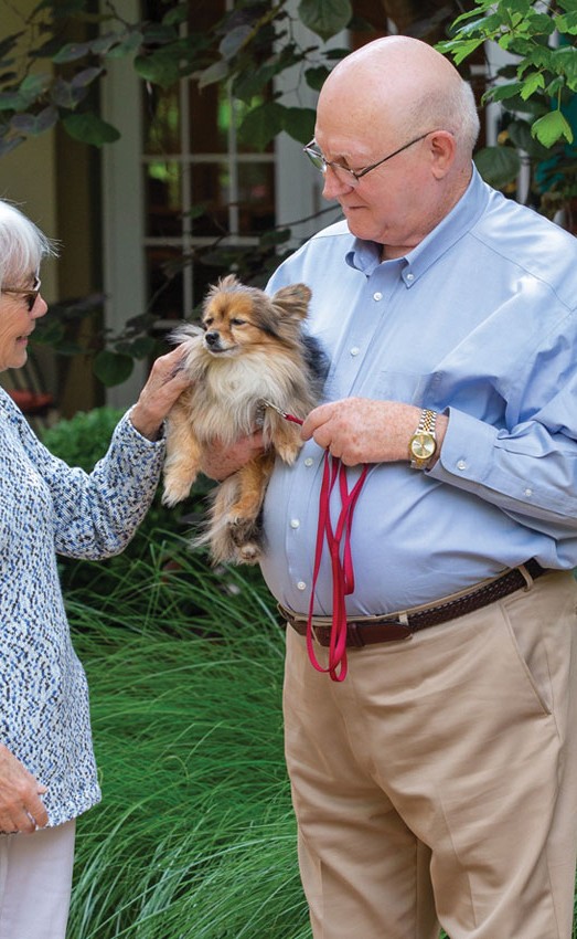 Woman petting a dog held by man outside