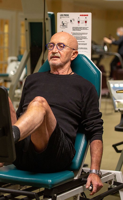 A resident exercising their legs in the gym.