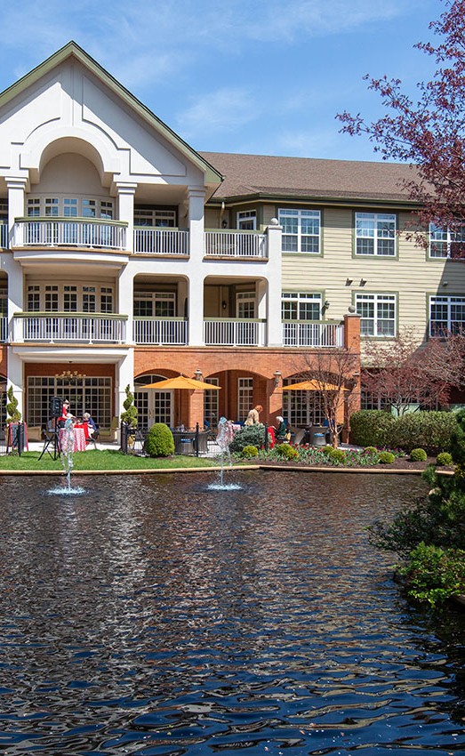 A sunny day looking at residents outdoors from across the pond.