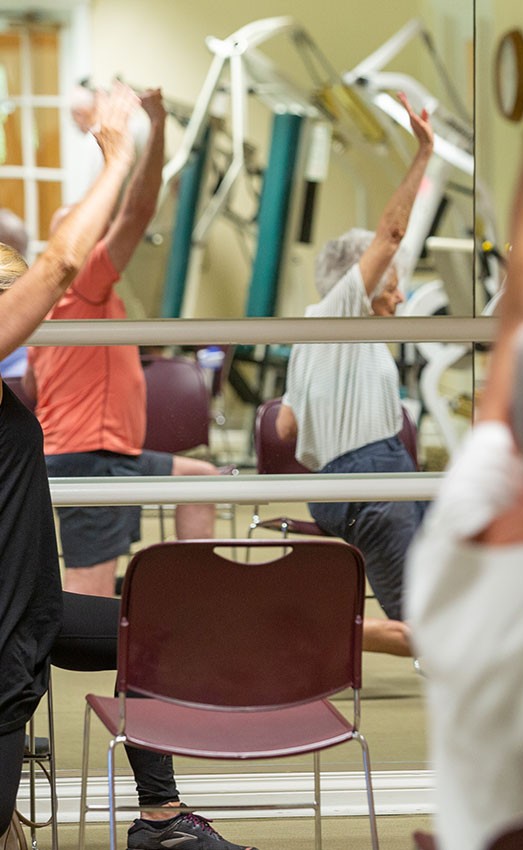 The Gatesworth exercise class with residents reaching in the air.