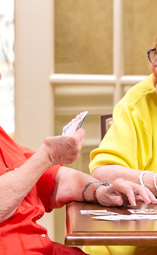 Two residents sitting at a table playing cards.