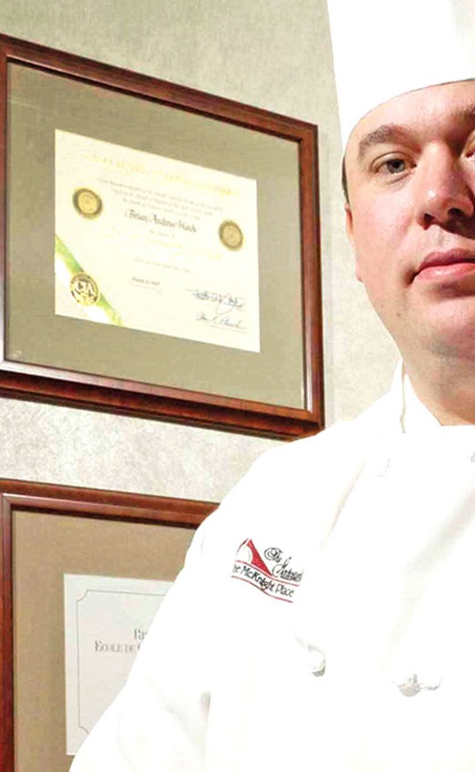 Executive Chef Brian Hardy in front of medals and certificates.