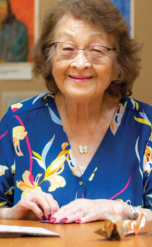 Resident sitting at a table making paper cranes.