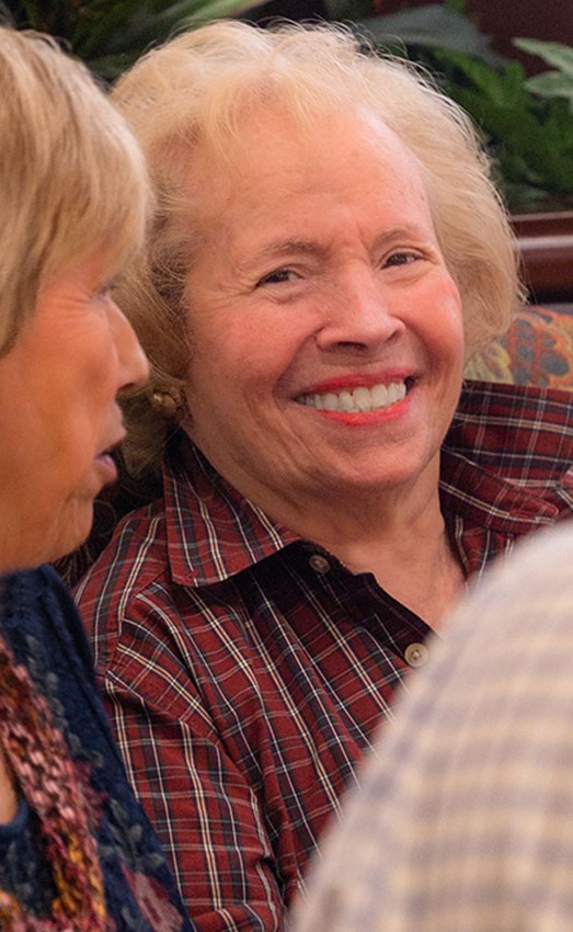 A resident sitting in a booth with others smiling.