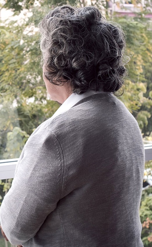 A woman looks out her window on an overcast day thinking.