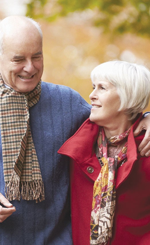 A couple walking outdoors in the fall with scarves on.