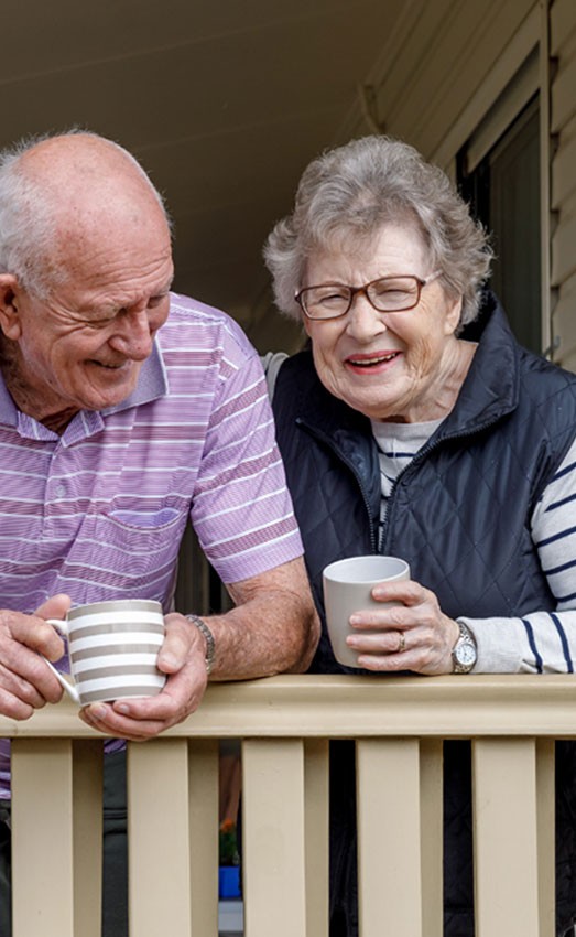 A husband and wife enjoying a warm drink on the porch.