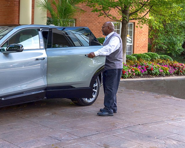 A staff member opens the door of a luxury car.