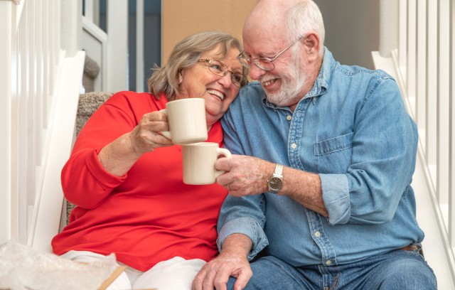 A couple enjoying coffee sitting on some steps.