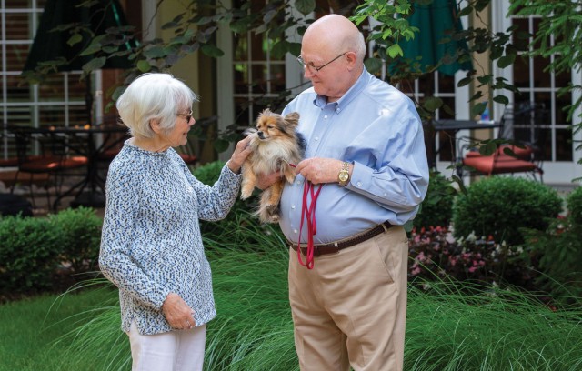 Woman petting a dog held by man outside