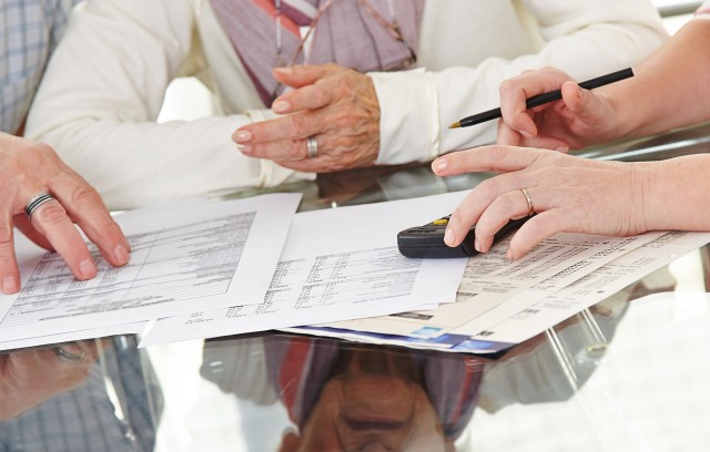 Closeup of three people discussing financial documents.