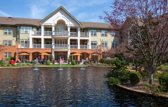 A sunny day looking at residents outdoors from across the pond.