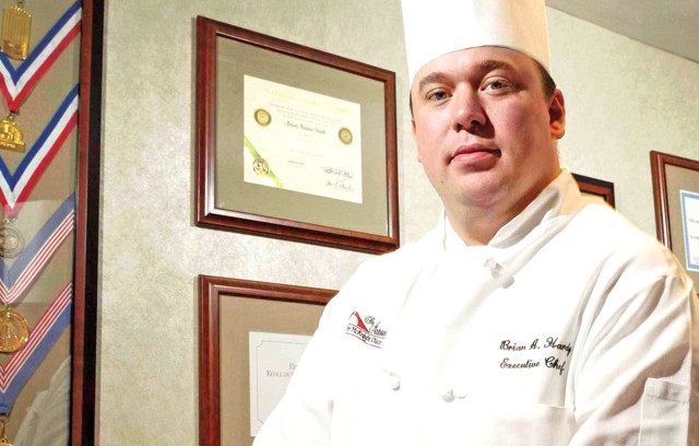 Executive Chef Brian Hardy in front of medals and certificates.