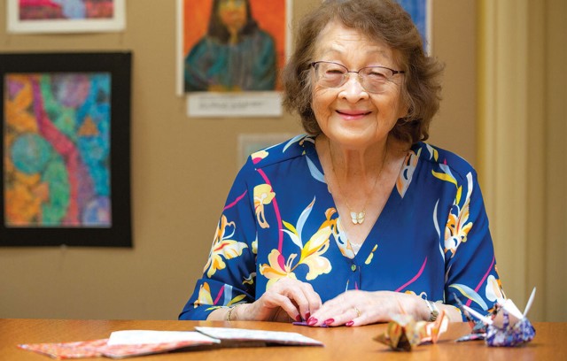 Resident sitting at a table making paper cranes.