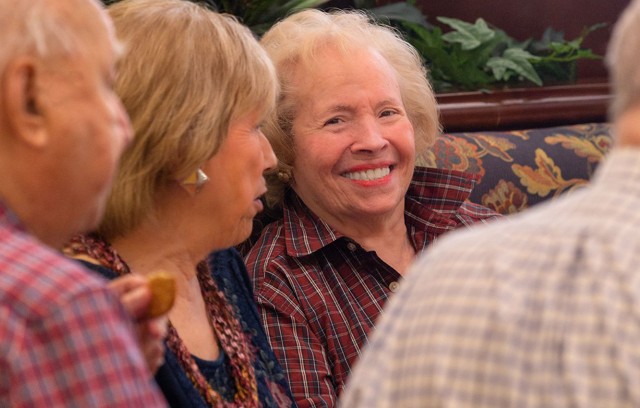 A resident sitting in a booth with others smiling.