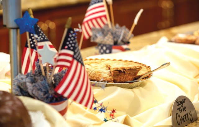 Cherry pie sitting on a dessert table with American flags.