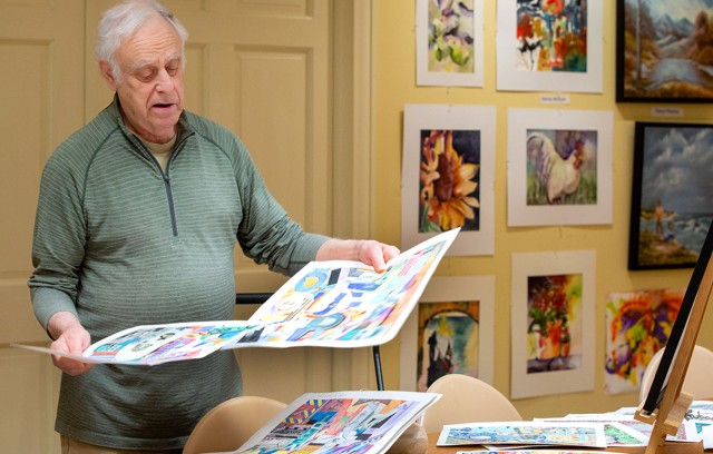 A man looks over his collection of artwork.