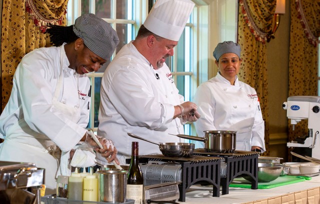 Three chefs cooking food in the dining room.