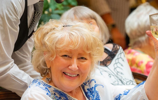 A woman raising a wine glass and smiling.