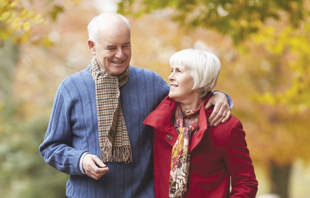 A couple walking outdoors in the fall with scarves on.