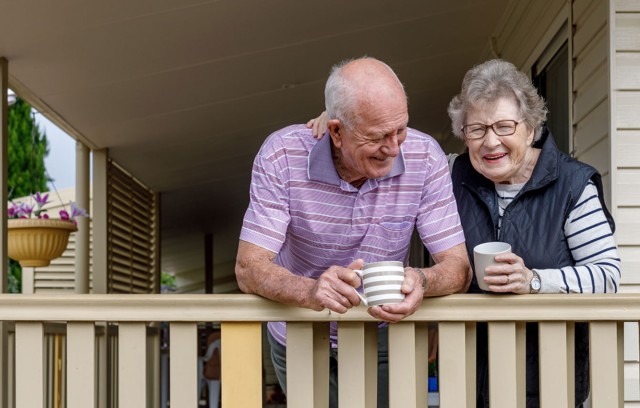 A husband and wife enjoying a warm drink on the porch.