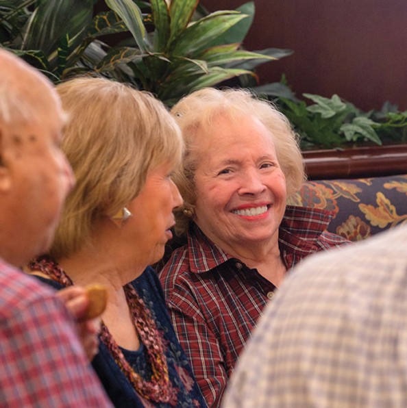 Residents sitting in a booth enjoying each other's company and smiling.