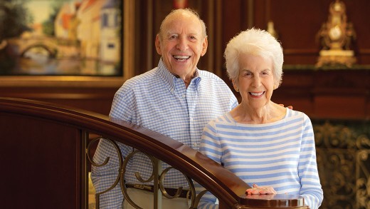 A couple stands in front of a staircase.