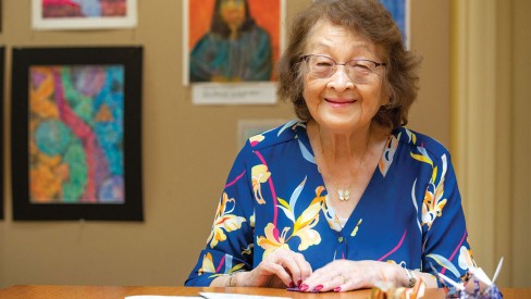Resident sitting at a table making paper cranes.