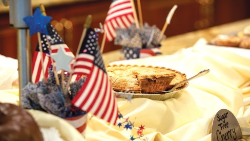 Cherry pie sitting on a dessert table with American flags.