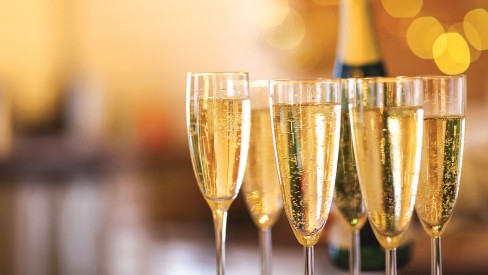 A close up of champagne glasses with lights in the background.