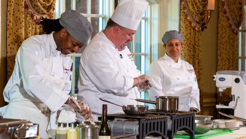 Three chefs cooking food in the dining room.