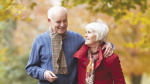 A couple walking outdoors in the fall with scarves on.