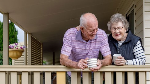 A husband and wife enjoying a warm drink on the porch.