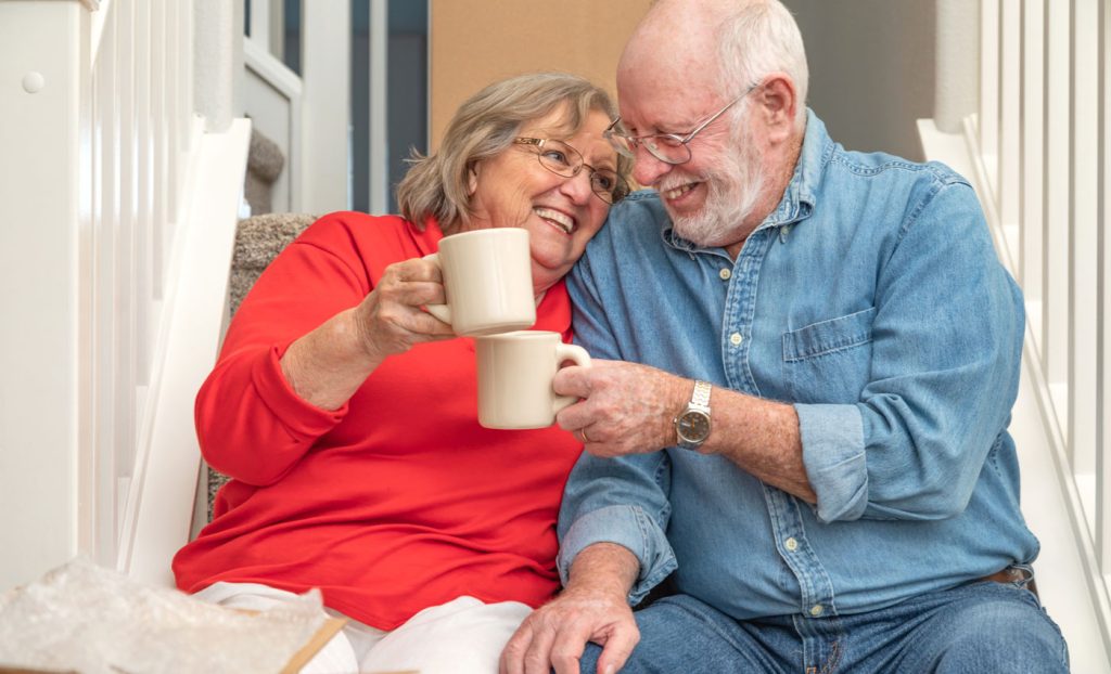 A couple enjoying coffee sitting on some steps.