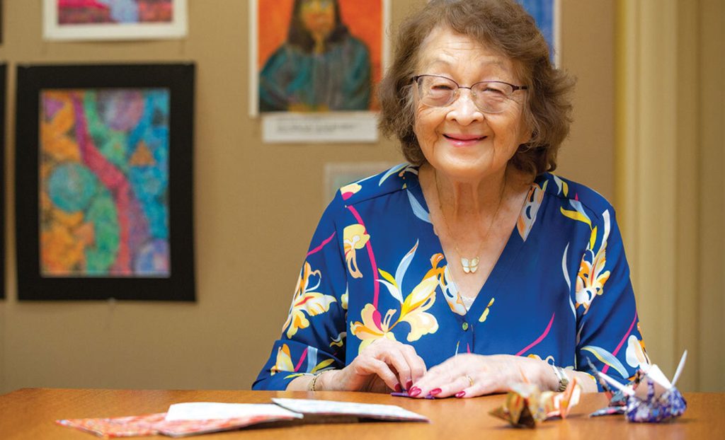 Resident sitting at a table making paper cranes.