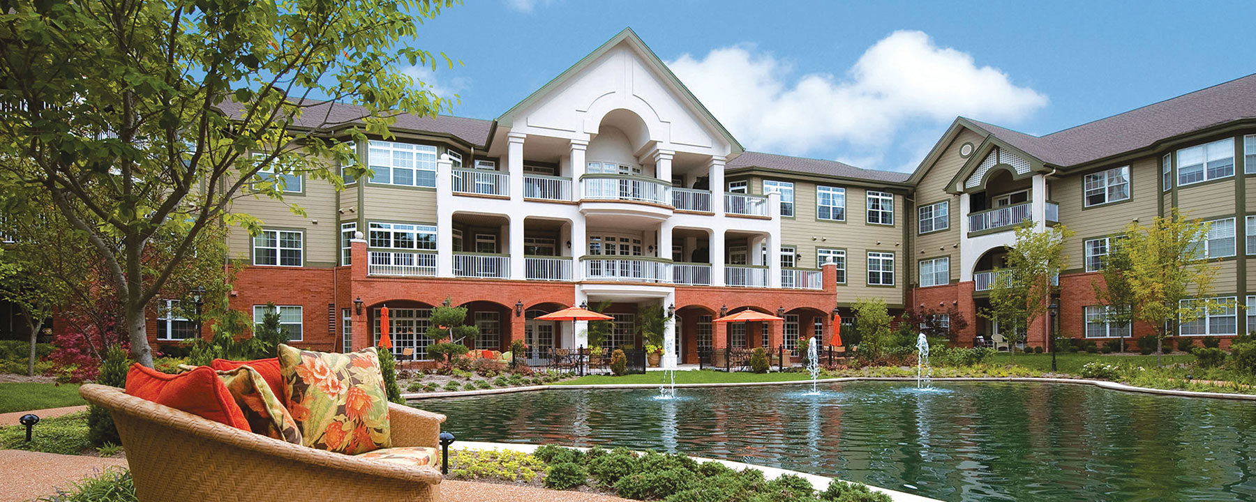 Exterior of The Gatesworth with a pond and seating area.